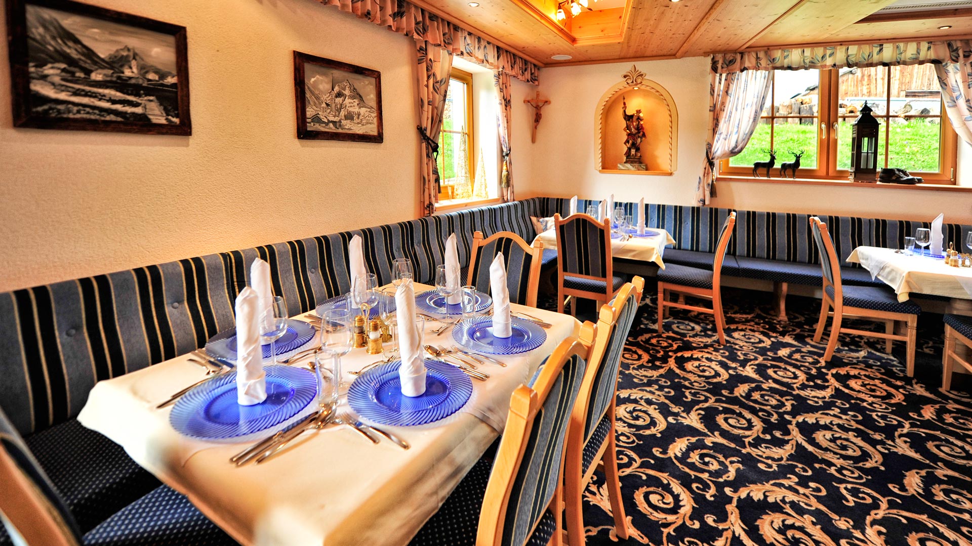 Gemütliches Restaurant mit festlich gedeckten Tischen, Holzdecke und traditionellem Dekor – alpenländische Atmosphäre.