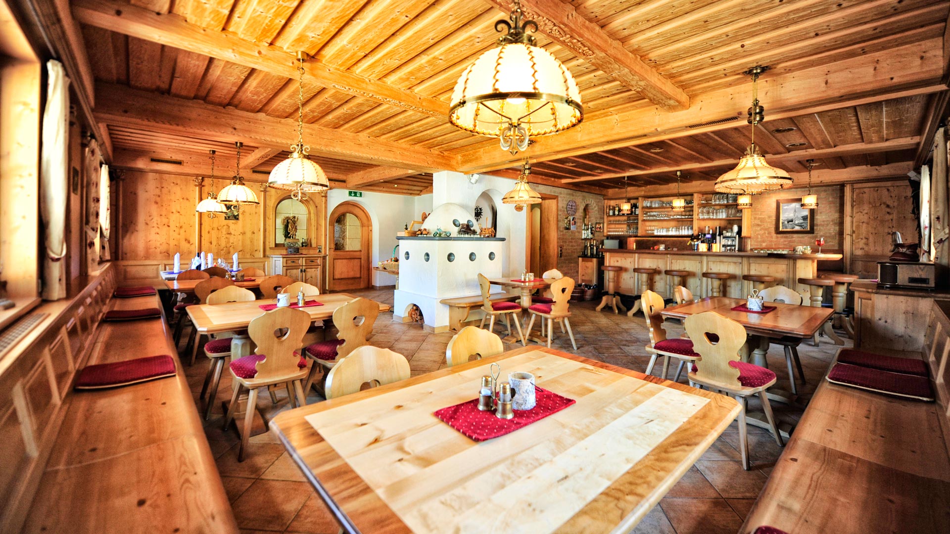 Traditionelle Tiroler Stube mit Holzmöbeln, Kachelofen und gemütlicher Beleuchtung – alpenländisches Ambiente pur.